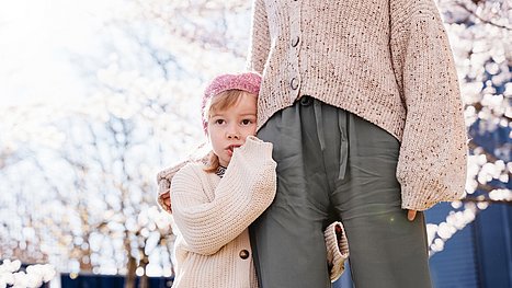 Kleines Mädchen hält mit den Händen den Mund zu.