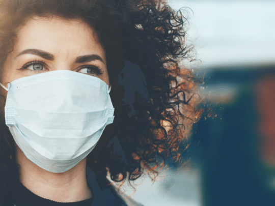Frau mit Locken und medizinischer Maske
