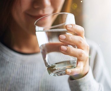 Frau trinkt ein Glas Wasser.