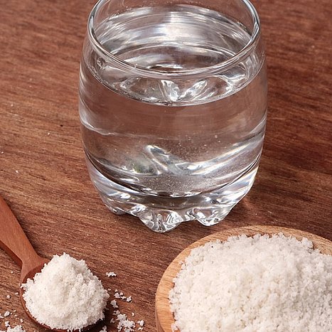 Gurgeln ist eine Wohltat bei einer Entzündung der Stimmbänder. Glas mit Wasser neben Holzschlüssel mit Salz.