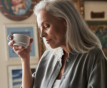 Eine Frau hält eine Tasse in der Hand.