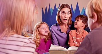 Frau liest Kindern ein Buch vor.