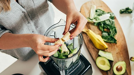 Gesunde Smoothie-Rezepte für starke Abwehrkräfte. Frau bereitet Zutaten für ein gesundes Smoothie-Rezept vor.