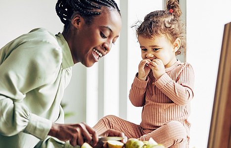 Mutter bereitet ihrer Tochter einen gesunden Snack vor.