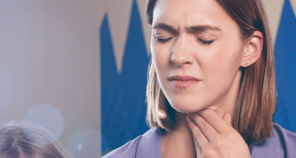 Frau greift sich mit der Hand an den Hals aufgrund von Halsbeschwerden